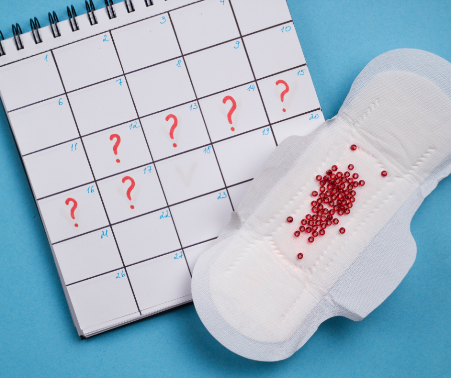 Kalender met vraagtekens bij de datums en een maandverband erbij, symbool voor een onregelmatige menstruatie en de zoektocht naar oplossingen