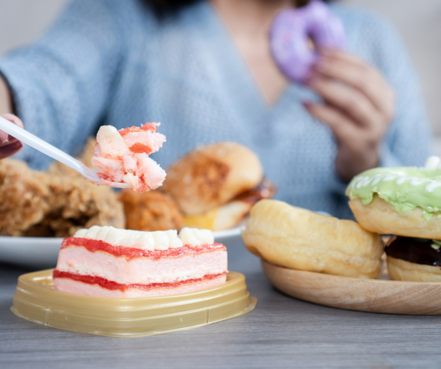 Vrouw die gebak, donuts en andere zoetigheid eet, met honger veroorzaakt door hormonen