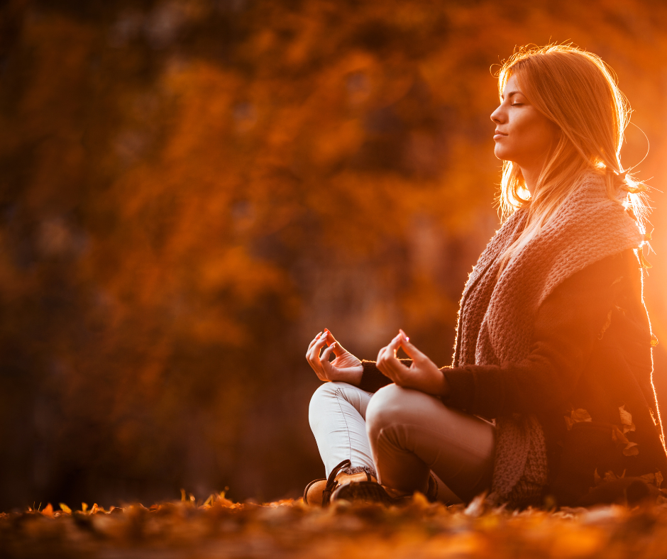 Vrouw mediteert in herfstnatuur, ervaart last van hormonen en herfstdipjes