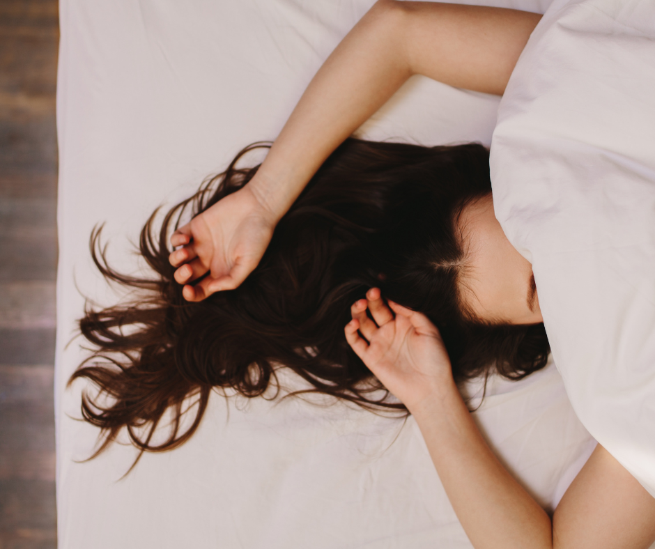 Vrouw ligt onder dekens en kan slecht slapen tijdens haar menstruatie