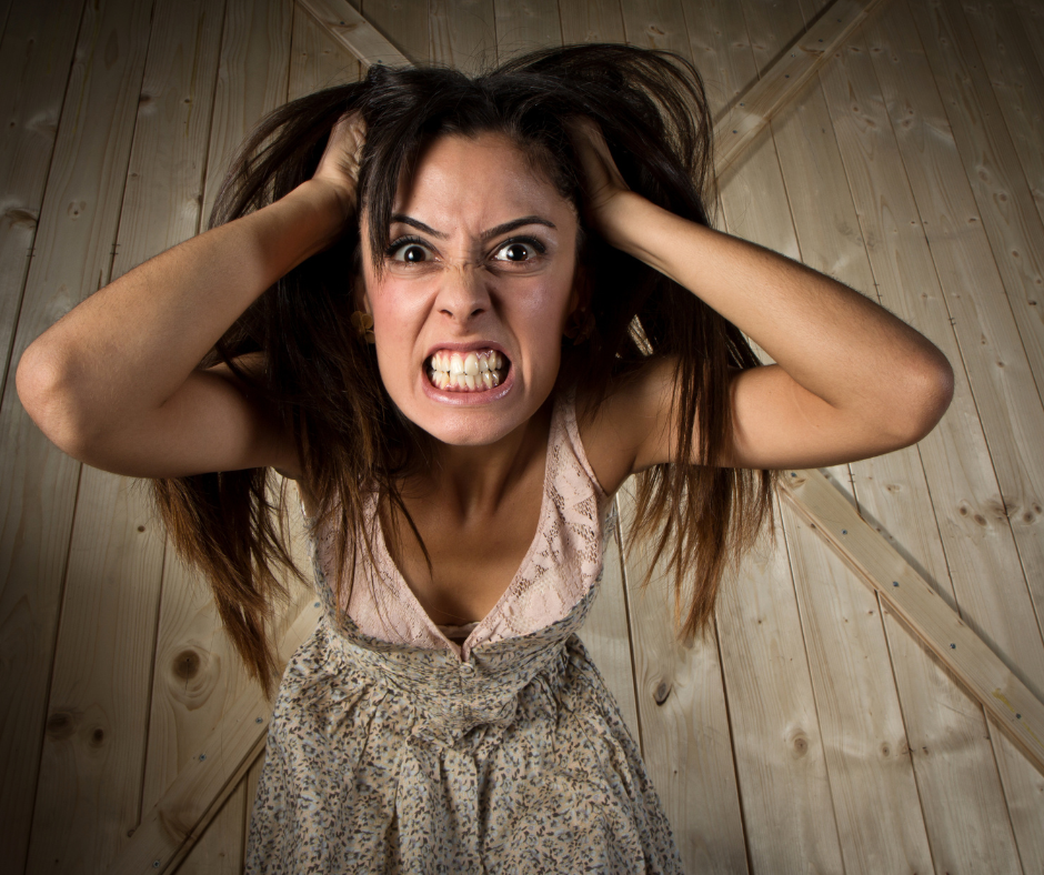 Vrouw houdt haar hoofd vast, zichtbaar gestrest en overprikkeld, illustratie van overprikkeling en hormonen bij vrouwen na de 40e