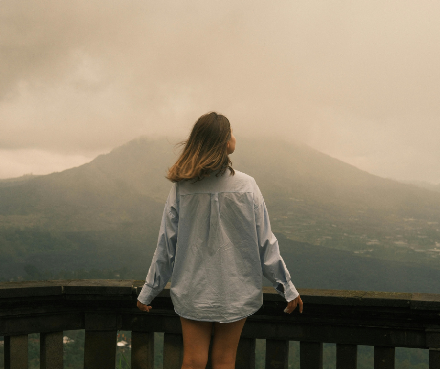 Vrouw die in de mist staat en zich dromerig en verward voelt, als symbool voor wazig denken en hormonen bij hormonale disbalans.