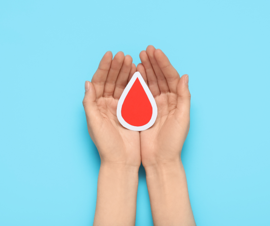 Bloedverlies voor menstruatie uitgebeeld met een hand die een druppel bloed vasthoudt als symbool voor spotting en hormonale disbalans.