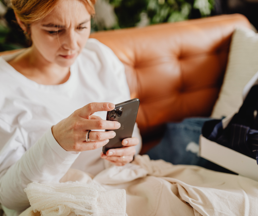 Vrouw scrollend op haar telefoon op de bank tijdens de avond, symbool voor stress, overprikkeling en hormonale disbalans door social media